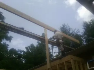 Carpenter setting a ridge beam over a new addition frame — Ice Dam Removal by Roofing Brothers in Icard