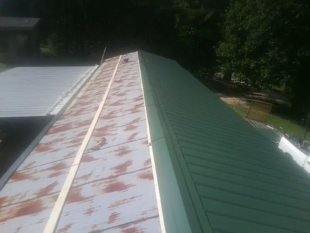 Old rusted panels beside newly installed green metal roofing — Wind Damage Roof Repair by Roofing Brothers in Icard