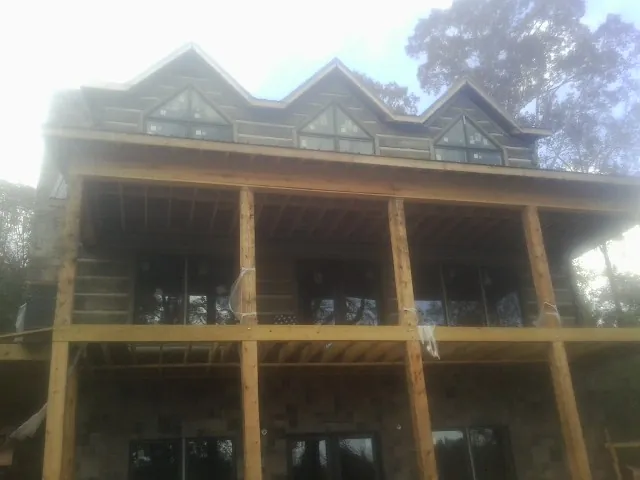 Dormers and porch framing on a large log home under construction — Roof Coating work by our crew in Icard