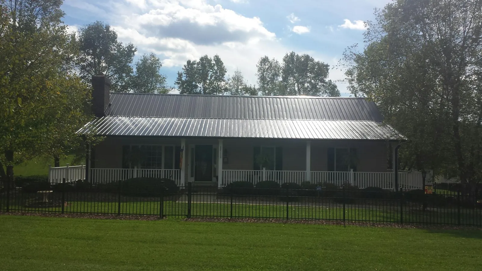 Gray metal roof on a brick ranch with a full width front porch — Gutter Guard Installation work by our crew in Icard