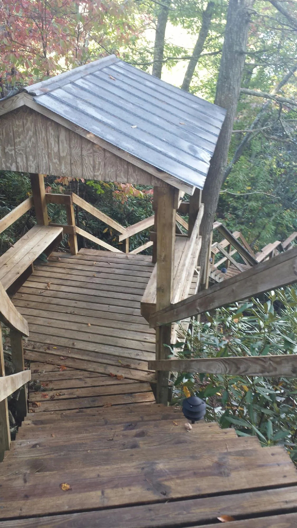 Metal roofed shelter over wooden steps on a wooded walkway — Skylight Repair & Installation work by our crew in Icard