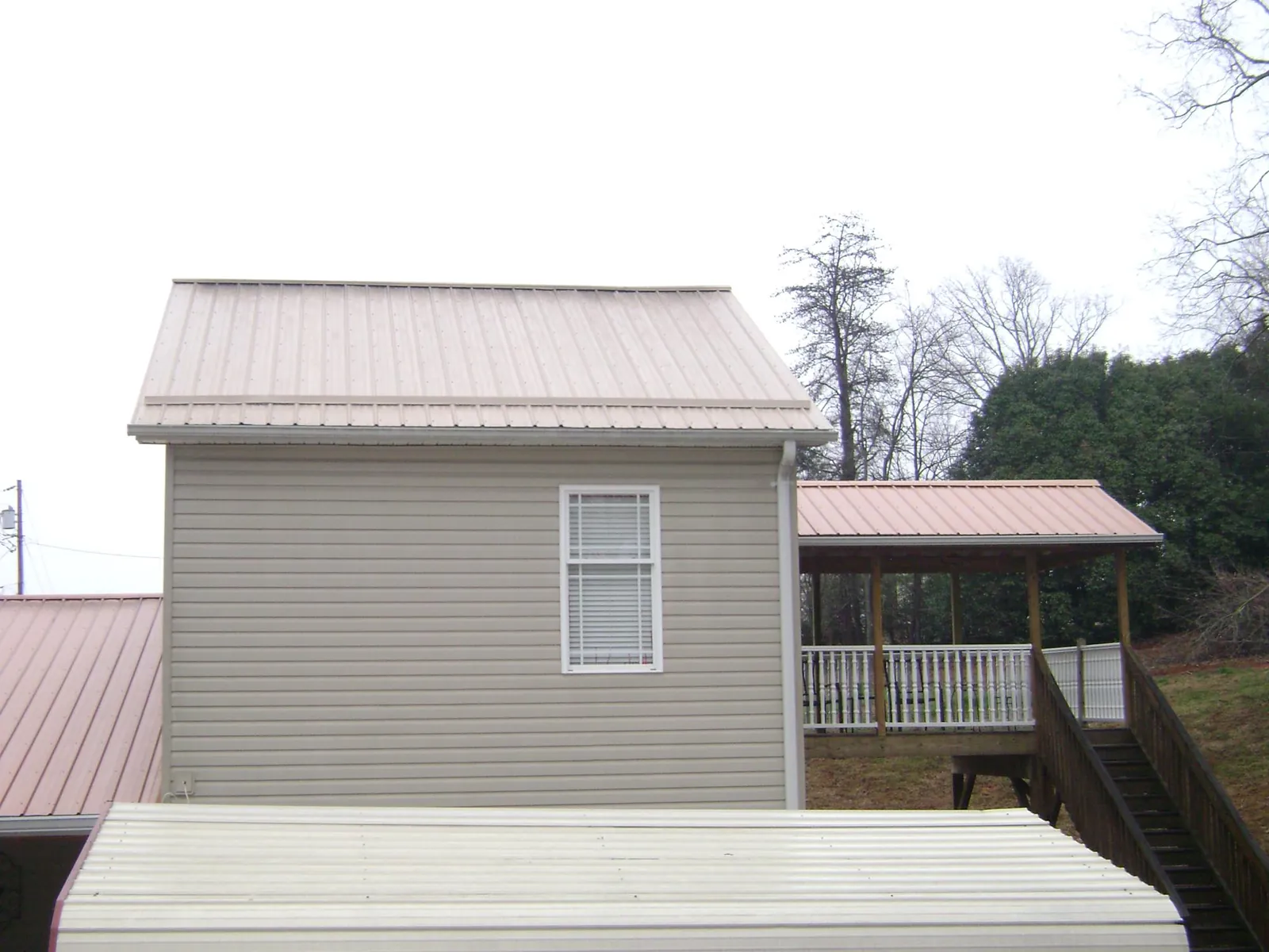 Tan metal roofs on a two story addition and attached porch, from a Roof Replacement job in Icard